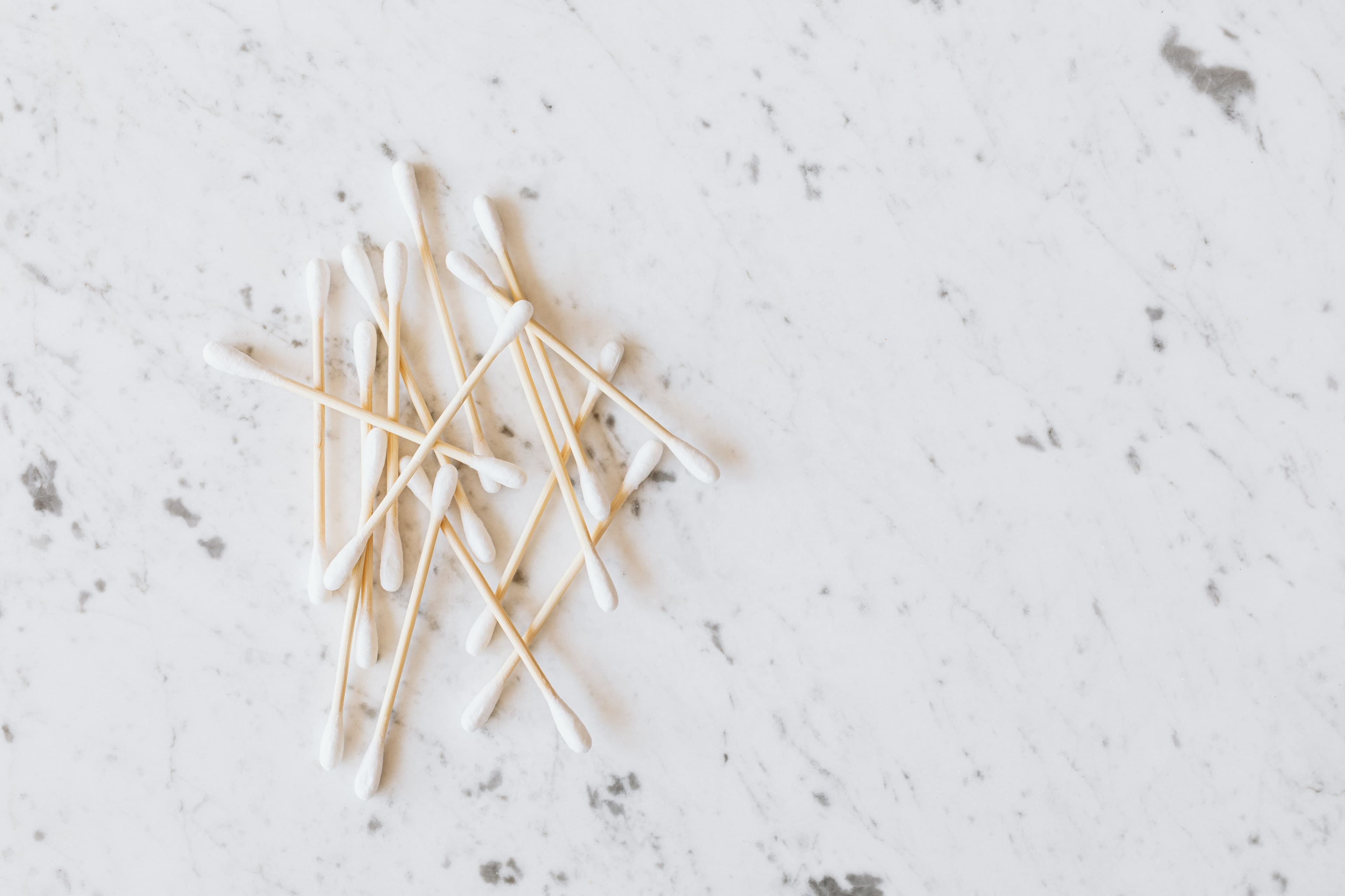 White cotton swabs with wooden stems on a pale marble surface